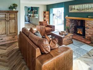 a living room with a leather couch and a fireplace at Normandy in Wyberton