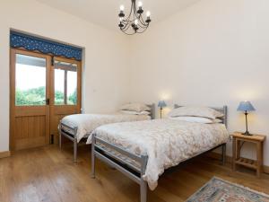 two beds in a bedroom with a chandelier at Parkers Lodge in Mathon