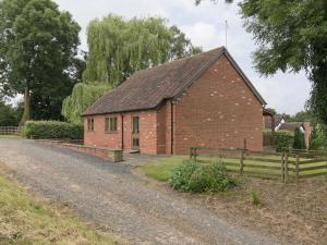 a brick building with a fence next to a road at Parkers Lodge in Mathon