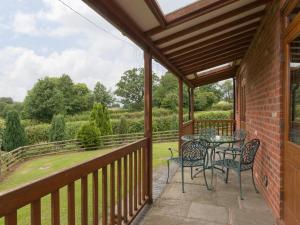 a patio with a table and chairs on a balcony at Parkers Lodge in Mathon +16 photos