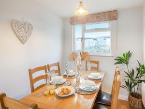 a dining room table and chairs with a wooden table and a window at Swyn Y Don in Llanfair +19 photos