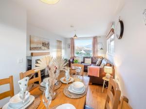 a dining room and living room with a table and chairs at Swyn Y Don in Llanfair