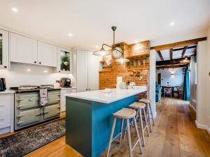 a kitchen with white cabinets and a blue island with bar stools at Mousehall Oast in Wadhurst