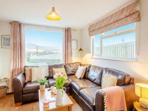 a living room with a leather couch and a large window at Swyn Y Don in Llanfair