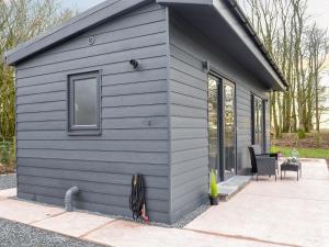 a gray tiny house with a window and a patio at Lime Tree Lodge in Castle Douglas