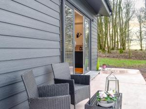 a patio with two chairs and a table at Lime Tree Lodge in Castle Douglas