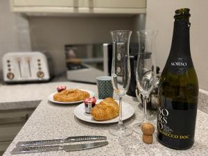a bottle of wine and two glasses and croissants on a counter at Clan Young Suite in Berwick-Upon-Tweed