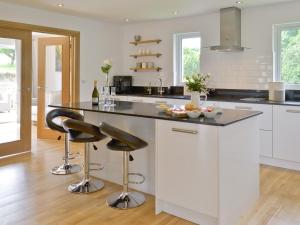 a kitchen with white cabinets and black counter tops at Florina in Cheriton Bishop