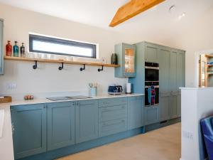 a kitchen with blue cabinets and a window at The Old Cowshed in Porchfield