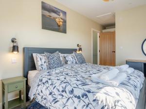a bedroom with a bed with a blue and white comforter at The Old Cowshed in Porchfield +32 photos