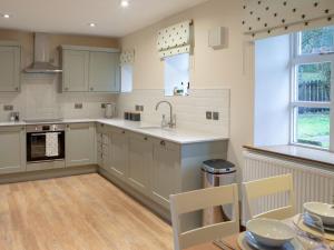 a kitchen with white cabinets and a sink and a table at Drumlanrig Mains Cottage - Uk7174 in Carronbridge