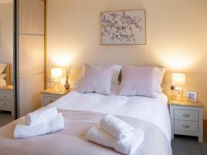 a bedroom with a white bed with towels on it at Drumlanrig Mains Cottage - Uk7174 in Carronbridge