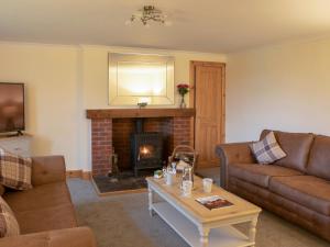 a living room with couches and a fireplace at Drumlanrig Mains Cottage - Uk7174 in Carronbridge