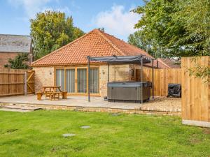 a patio with an umbrella and a grill at Tawny Acre Barn - Uk38614 in Wisbech