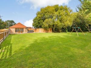 a large yard with a swing set in the yard at Tawny Acre Barn - Uk38614 in Wisbech