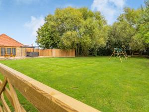 a large yard with a wooden fence and a playground at Tawny Acre Barn - Uk38614 in Wisbech +40 photos