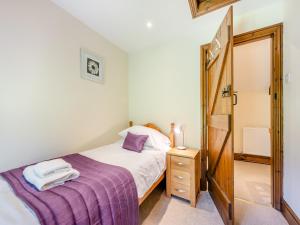 a small bedroom with a bed and a wooden door at Rhandir Barn in Ffair-fâch
