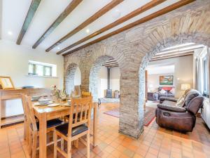 a living room with a table and a stone wall at Rhandir Barn in Ffair-fâch