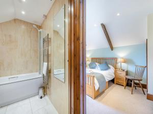 a bedroom with a bed and a bathroom with a tub at Rhandir Barn in Ffair-fâch