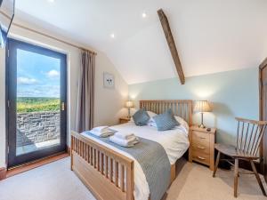 a bedroom with a bed and a large window at Rhandir Barn in Ffair-fâch