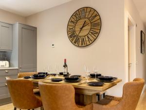 a dining room table with a large clock on the wall at Slatehouse Cottage - Uk7562 in Carronbridge