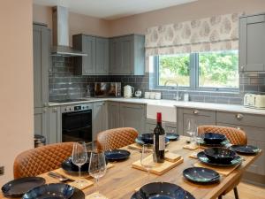 a kitchen with a wooden table with wine glasses at Slatehouse Cottage - Uk7562 in Carronbridge