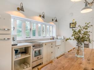 a kitchen with white cabinets and a wooden floor at The Ostlers Cottage in Sleaford