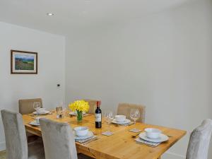 a wooden table with chairs and a bottle of wine at Cunliffe Cottage in Hathersage