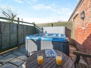 a hot tub and a table with two glasses of orange juice at One Chainbridge Barns in Skegness