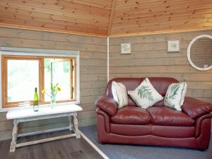 a red leather couch in a room with a table at Mallard Roundhouse - Uk33891 in Cullompton +10 photos