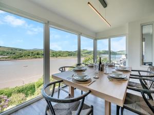 a dining room with a table and chairs with a view of the water at Berkeley in Kippford
