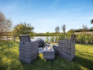 three wicker chairs and a table in a yard at Clay Lake Cottages - Dad's Shed in Covenham
