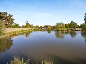 a large lake with trees and houses in the background at Clay Lake Cottages - Dad's Shed in Covenham