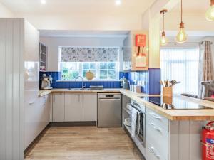 a kitchen with white cabinets and blue walls at The Gables in Bridlington