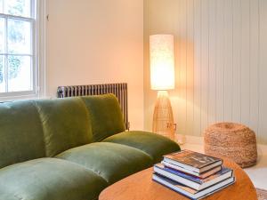 a living room with a green couch and a table with books at Yew Tree House Cottage in New Romney