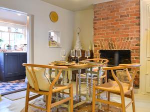 a dining room with a table and chairs and a brick fireplace at Yew Tree House Cottage in New Romney