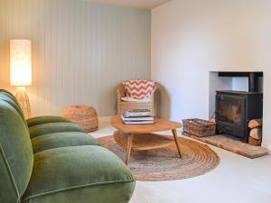 a living room with a green couch and a wood stove at Yew Tree House Cottage in New Romney