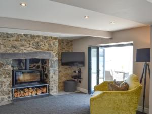 a living room with a stone fireplace and a yellow chair at Tan Y Fford in Bangor