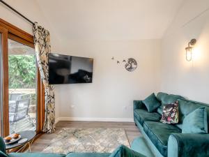 a living room with a green couch and a tv at River Retreat-B6842 in Brundall