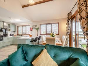 a living room with a green couch and a kitchen at River Retreat-B6842 in Brundall