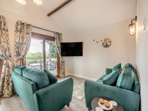 a living room with two blue chairs and a tv at River Retreat-B6842 in Brundall
