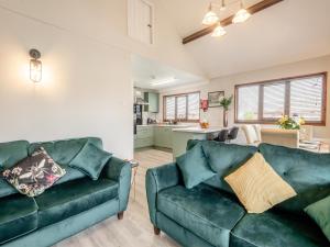 a living room with two green couches and a kitchen at River Retreat-B6842 in Brundall