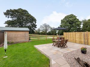 a patio with a table and chairs and an umbrella at Sycamore Lodge - Uk35106 in Chapel Saint Leonards