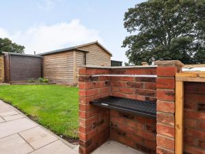 a brick retaining wall with a bench in a yard at Sycamore Lodge - Uk35106 in Chapel Saint Leonards