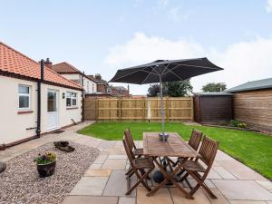 a table and chairs with an umbrella in a backyard at Sycamore Lodge - Uk35106 in Chapel Saint Leonards +13 photos