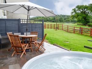 a patio with a table and chairs and an umbrella at Sgubor Llwyndu in Bettws