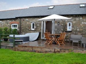 a patio with a table and an umbrella at Sgubor Llwyndu in Bettws