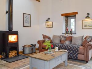 a living room with a couch and a wood stove at Sgubor Llwyndu in Bettws +23 photos