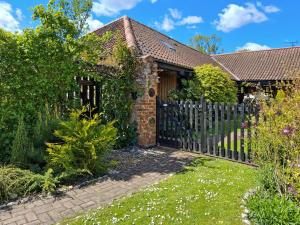a brick house with a wooden fence at Bockety Barn in Stalham