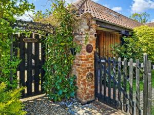 a brick house with a fence and a gate at Bockety Barn in Stalham